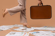 © Pixel-Shot - Legs of woman in high heels with many newspapers and suitcase on brown background, closeup