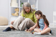© New Africa - Nanny and cute little girl playing with wooden pieces on floor indoors