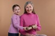 © New Africa - Little girl greeting her grandmother with gift on dark beige background