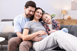 © New Africa - Pregnant woman, her husband and daughter on sofa at home