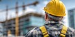 © NovaVision - Construction worker in yellow hard hat looking at building site with cranes and new structures
