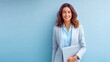 © NovaVision - A happy businesswoman in a suit holds a laptop, ready to work.