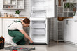 © Pixel-Shot - Male worker with tools repairing refrigerator in kitchen