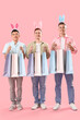 © Pixel-Shot - Young men in bunny ears with shopping bags on pink background. Easter Sale