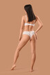 © Pixel-Shot - Beautiful young woman in white lace underwear on brown background, back view