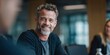 © NovaVision - Smiling middle-aged man with graying hair and beard in a business meeting setting