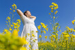 © mei - A young woman spreading her arms in a spring rapeseed flower sea
