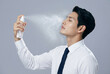 © BTree - Man applies skin spray in a studio setting during daytime for skincare routine