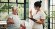 © peopleimages.com - Physical therapy, thumb up and old woman with dumbbells, fitness and motivation for exercise routine. Happy, senior person and physiotherapist with tablet for health progress or workout in clinic