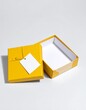 © Rindi - Open and closed yellow realistic cardboard box with paper and a sticker on a light background. The concept of business gifts. Mock up.