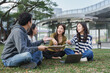 © crizzystudio - Young students group discussing outdoors on campus grass
