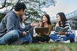 © crizzystudio - Young asian students discussing ideas on university campus grass