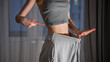 © Alisa - Happy young woman showing weight loss success by wearing oversized pants and giving a thumb up. Fitness motivation for spring, healthy lifestyle, and body transformation at home. Getting in shape.