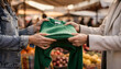 © Oleksandr - Two individuals exchange a vibrant green sweater, highlighting consumer interaction and apparel selection at an outdoor market stall, with focus on hands and clothing