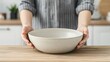 © Jack - A modern kitchen interior captured as an emotional connection lifestyle photo, showing hands passing a ceramic bowl across a wooden dining table.