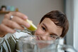 © Seventyfour - Portrait of boy smiling while squeezing lemon slice into glass pitcher, focusing on hand movement and facial expression, demonstrating preparation of fresh drink