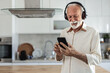 © Jelena Stanojkovic - Senior man, headphones and retirement for music, relax and positive mood on weekend with radio in house. One person, listening and happy in living room for podcast, streaming or jazz with happiness.