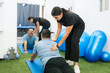 © Carlos Flores - Physiotherapist assisting man with back rehabilitation exercise