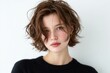 ©  Sheton - 하얀색 배경 앞에서 검은색 니트 스웨터를 입고 자연스러운 웨이브가 들어간 갈색 숏컷 헤어스타일을 뽐내며 정면을 응시하고 있는 매력적이고 우아한 분위기의 젊은 여성 인물 초상화 이미지.