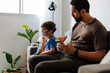 © kleberpicui - Father sitting beside child during nebulizer treatment at home, illustrating emotional support, pediatric healthcare and daily family caregiving routine.