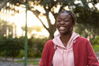 © wavebreak3 - African American teen in pink hoodie walking, smiling on paved path near green lamppost, copy space