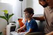 © kleberpicui - Father assisting young child during nebulizer therapy at home, showing parental care, pediatric respiratory treatment and emotional family support.