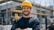 © Maksym - Close-up environmental portrait of a construction worker outdoors with safety helmet and gloves, bright friendly expression, blurred scaffolding and ladders behind him, shallow dep
