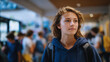 © Maksym - Side-angle shot of a student walking slowly down a school corridor, blurred groups of peers interacting in the background, muted colors and shallow depth of field emphasizing lonel