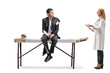 © Ljupco Smokovski - Female doctor talking to a businessman in a torn suit sitting on a massage table