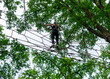 © Stefanie - Young girl balancing on rope bridge in forest adventure park