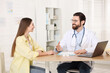 © New Africa - Woman having appointment with doctor at wooden desk in clinic