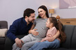 © New Africa - Pregnant woman, her husband and daughter on sofa at home