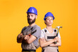 © DC Studio - Caucasian builders pose in overalls with arms crossed expressing readiness for repair tasks. Team of renovators with tools in hand, facing camera in studio, suitable for handyman service advertising.