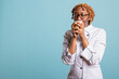 © DC Studio - Portrait of tired female chef wearing glasses and uniform, standing in studio with coffee mug. Overworked restaurant worker enjoying caffeine aroma with eyes closed, having relaxing moment after work.