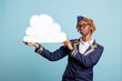 © DC Studio - Air hostess in cabin crew uniform holding cloud shaped signboard, empty mockup template for airline branding. Confident flight attendant presents area for product display or aviation services.