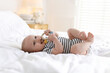 © New Africa - Cute little baby with teether on bed at home