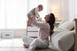 © New Africa - Smiling mother holding her cute baby near sofa on floor at home. Space for text