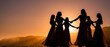 © Yuliia - Silhouettes of five women holding hands in circle formation against dramatic sunset sky over mountain landscape creating powerful unity and sisterhood moment.