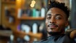 © Yuliia - Young African American man with beard relaxing in modern barbershop chair, professional grooming service, male lifestyle and self-care concept.