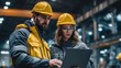 © LimeSky - Male and female industrial engineers in hard hats collaborate on a new project using a laptop at a heavy manufacturing facility dressed in safety jackets