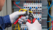 © Creative  - electrician at work, Repairing the system, Following safety rules, Typical industrial work, Performing routine maintenance, Electrician works panel, Wearing safety gloves