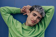 © VISTA by Westend61 - Portrait of playful young adult relaxing with hands behind head outdoors