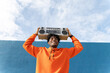 © VISTA by Westend61 - Person in orange holding boombox overhead smiling in Barcelona outdoors