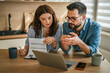 © Miljan Živković - Couple discussing budget and finances at home kitchen desk