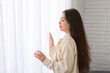 © Pixel-Shot - Young Asian woman near light curtains at home