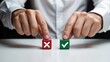 © shakilhossain - Close-up of a person choosing between red cross and green checkmark wooden cubes