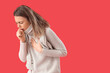 © Pixel-Shot - Ill young woman coughing on red background