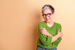 © deagreez - Confident mature lady in green sweater smiles warmly against beige background casual style fashion for lifestyle advertising campaigns
