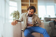 © Dragana Gordic - Man With Stomach Pain Grabbing Abdomen While Sitting On Couch At Home, Looking Distressed