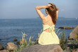 © zhagunov_a - Woman in yellow dress sitting on seaside rocks